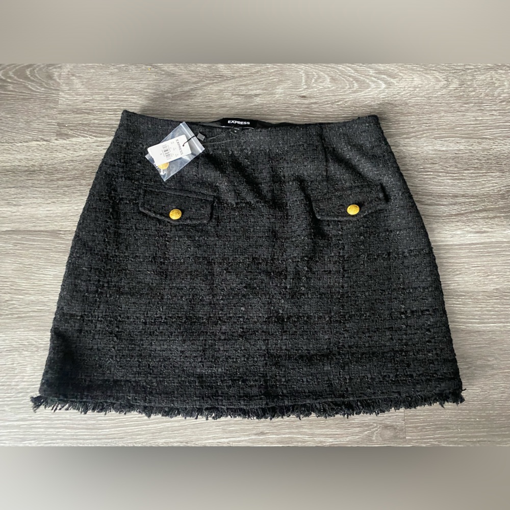 Black skirt with two pocket detailing on the front with gold buttons.